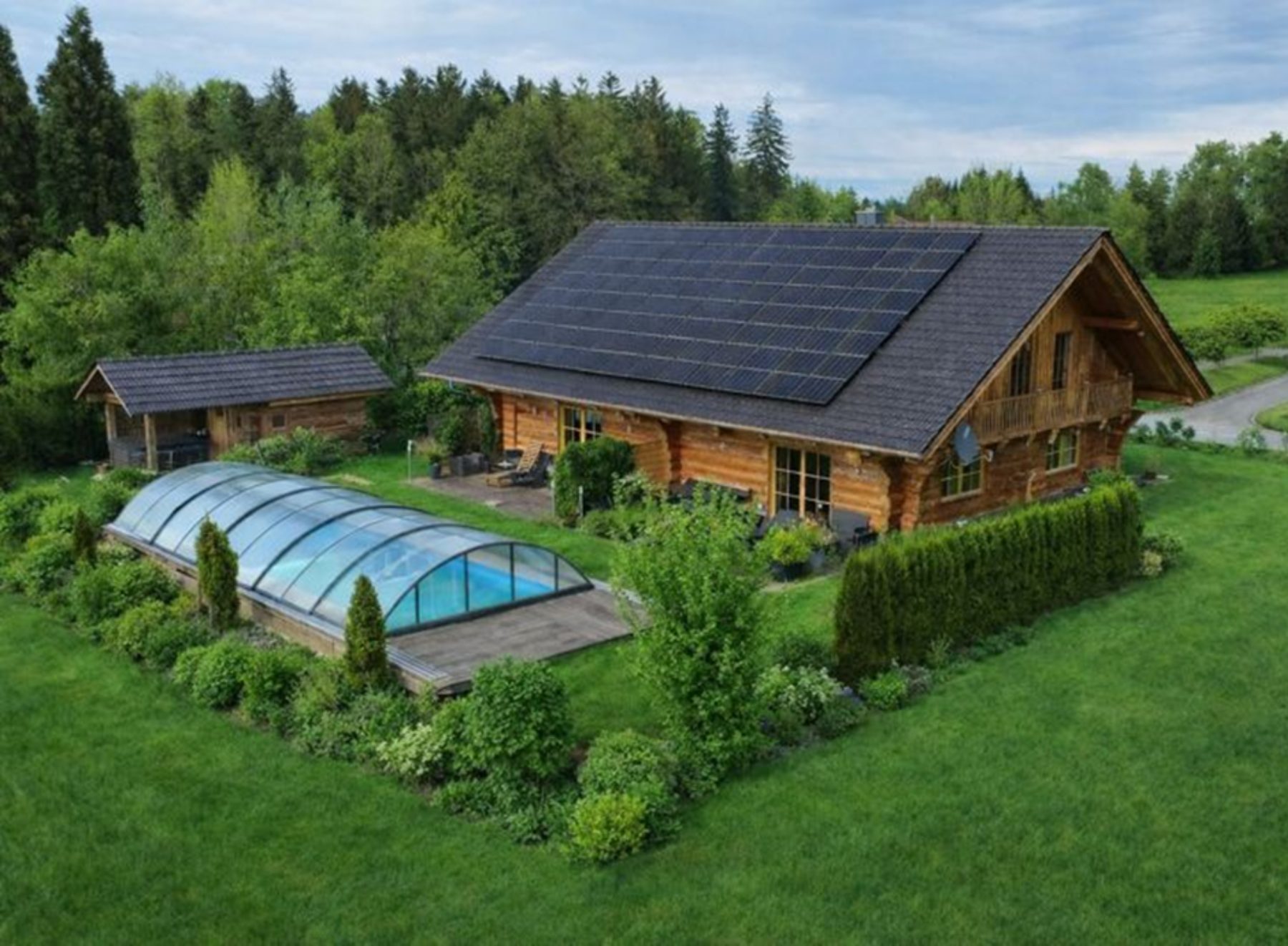 Luftaufnahme von Blockhaus, Garten und überdachtem Pool
